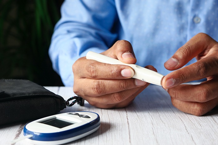 Una persona usando un dispositivo médico para medir el nivel de glucosa en sangre.