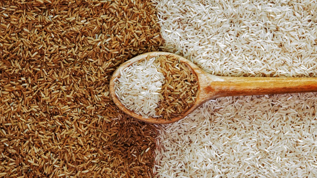 Una cuchara de madera dividiendo arroz integral y arroz blanco.