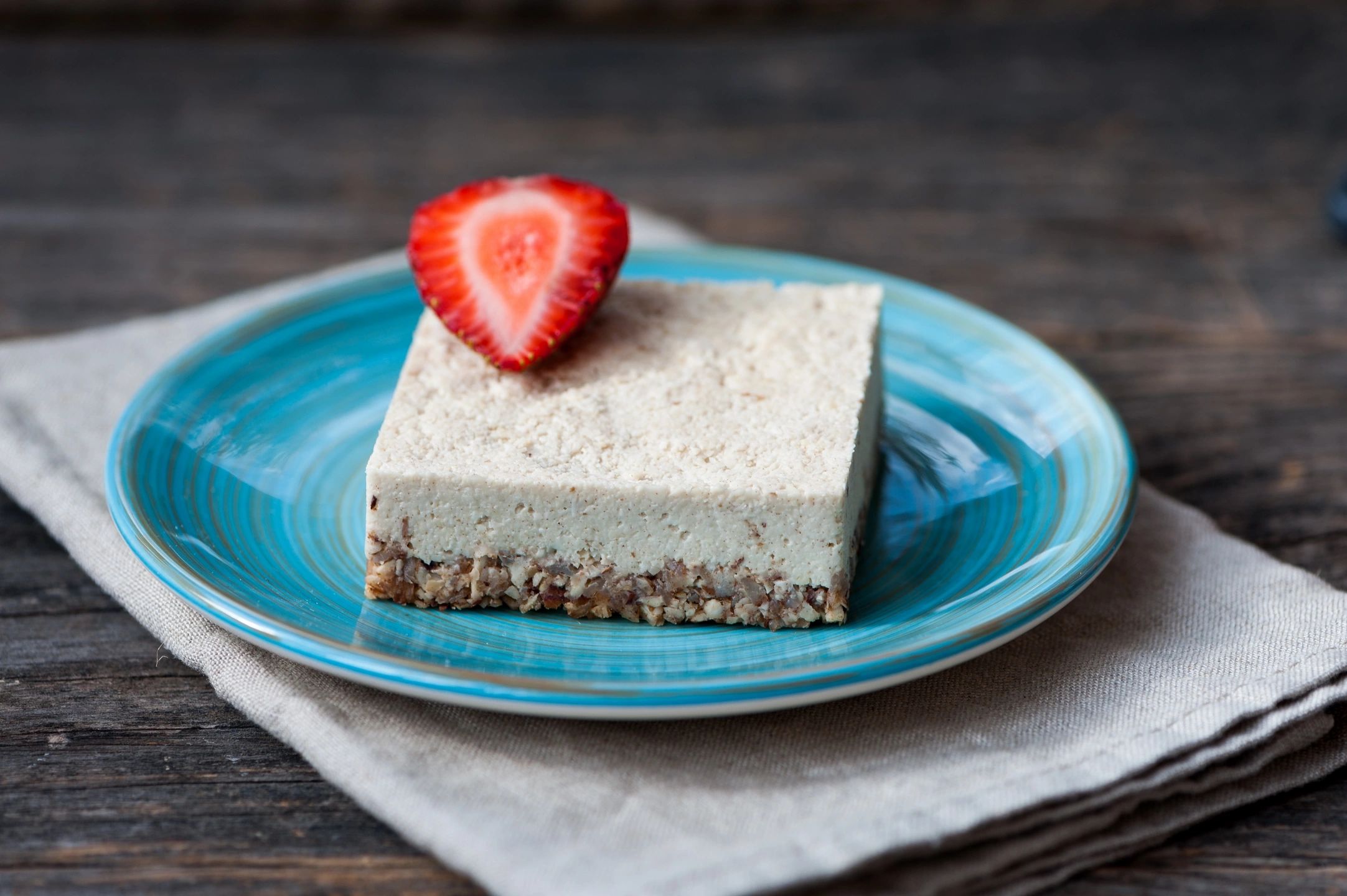 Porción de un postre en un plato azul turquesa con una fresa en la parte superior.