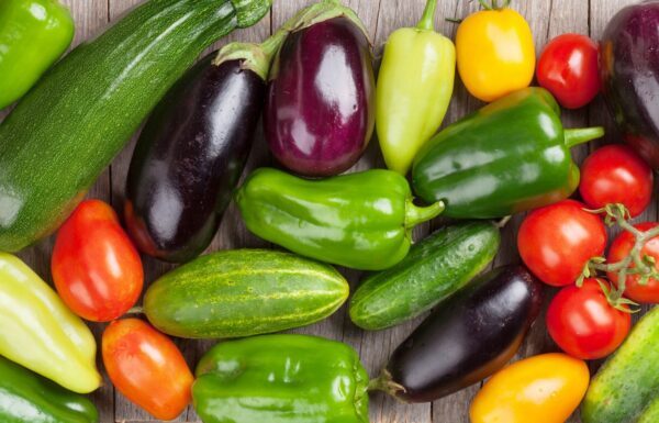 Variedad de verduras frescas y coloridas dispuestas sobre una superficie de madera.