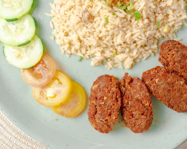 Plato de comida con arroz, albóndigas y rodajas de verduras.