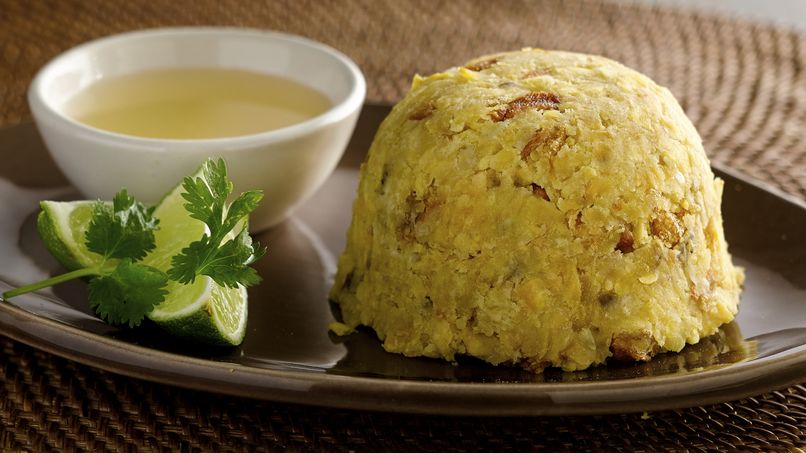 Plato de mofongo acompañado de caldo y de limón.