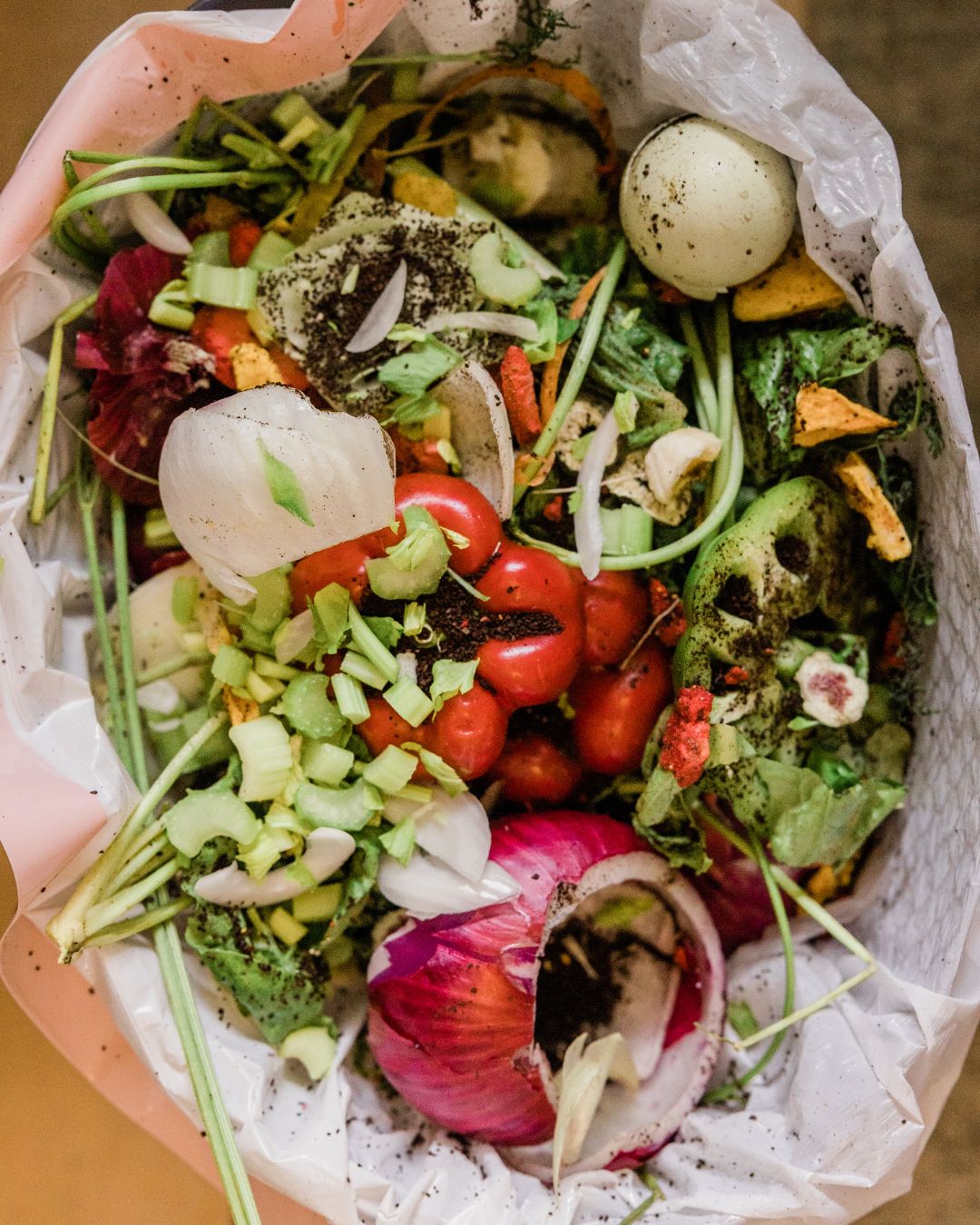 Una bolsa de basura llena de desechos de vegetales y comida.