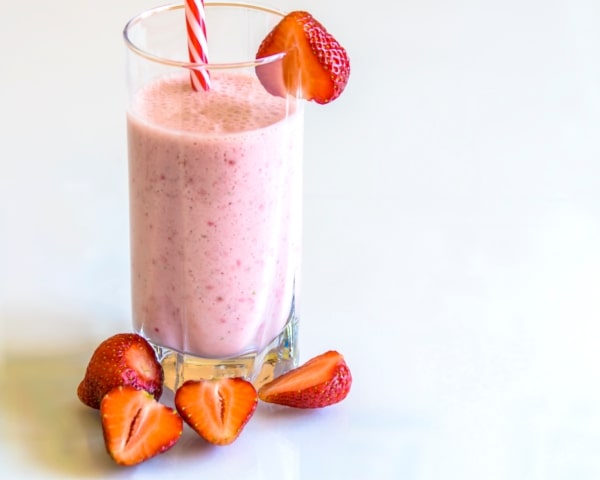 Batida de fresa cremosa con frescas alrededor.