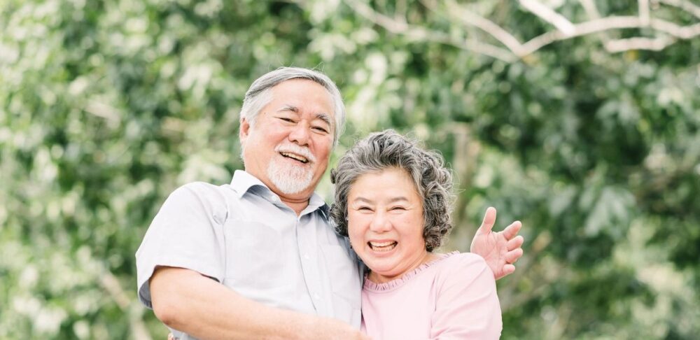 Una pareja de ancianos sonriendo y abrazándose en un parque.