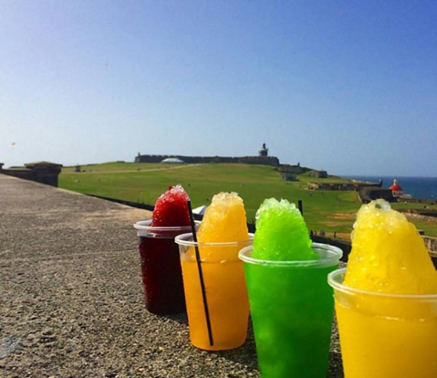 Piraguas de colores con el histórico Castillo San Felipe del Morro de fondo.