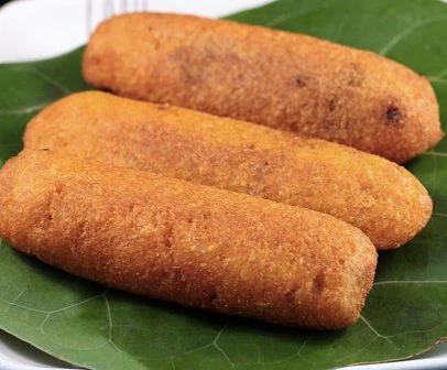 Tres alcapurrias doradas descansando sobre una hoja de plátano en un plato blanco.