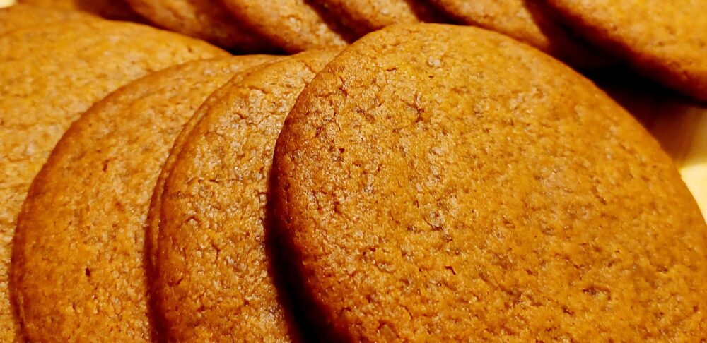 Un plato con varias galletas Cuca marrones, dispuestas en una fila. Las galletas tienen una textura suave y están doradas uniformemente.