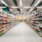 Pasillo de supermercado con estantes llenos de productos ultra-procesados y alimentos empacados en ambos lados.