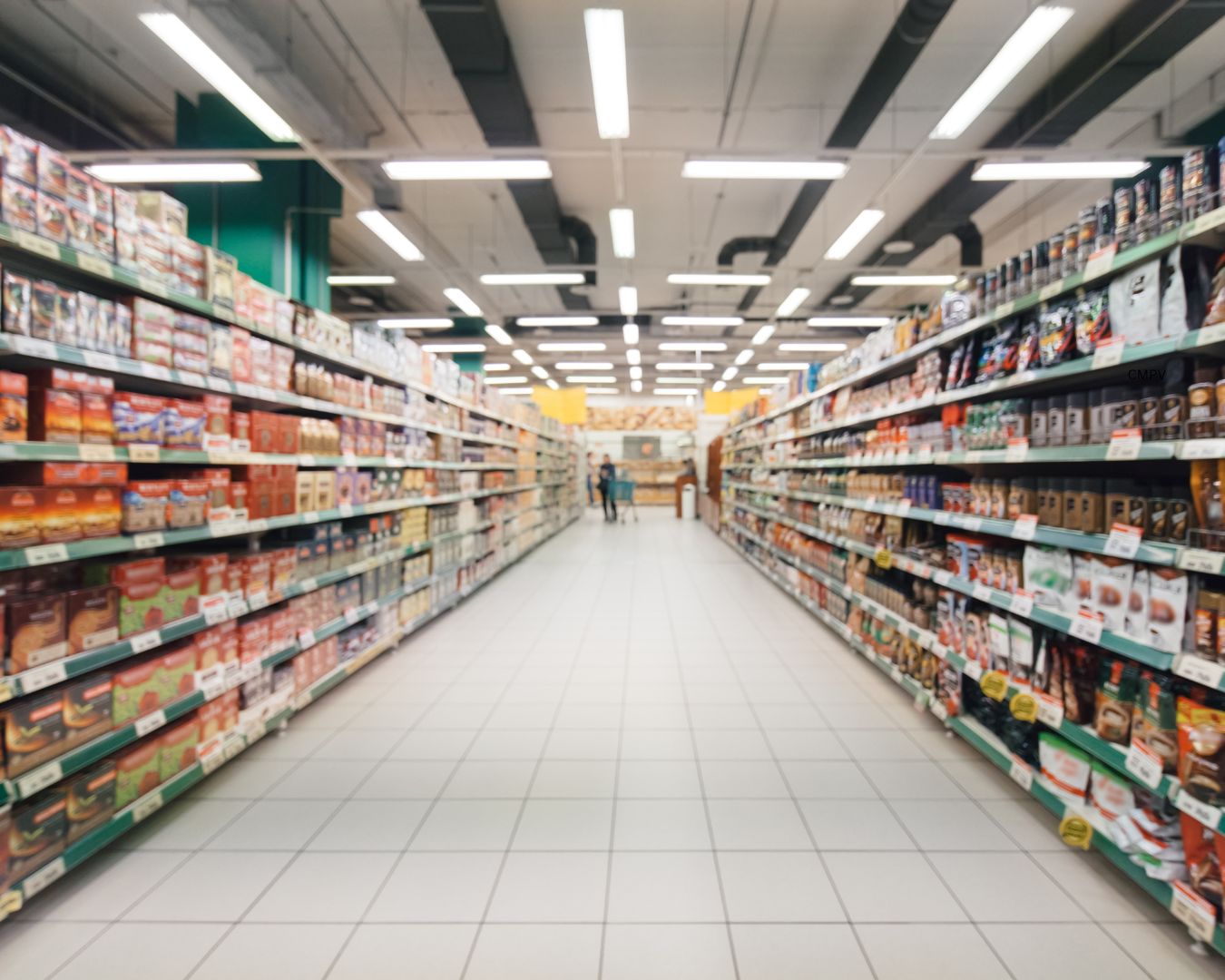 Pasillo de supermercado con estantes llenos de productos ultra-procesados y alimentos empacados en ambos lados.