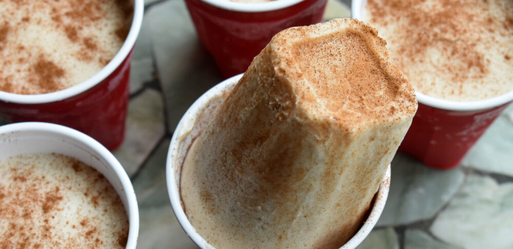 Vasos rojos con Limbers de Coco con canela, un postre congelado tradicional de Puerto Rico, uno de ellos parcialmente desmoldado mostrando su textura cremosa.