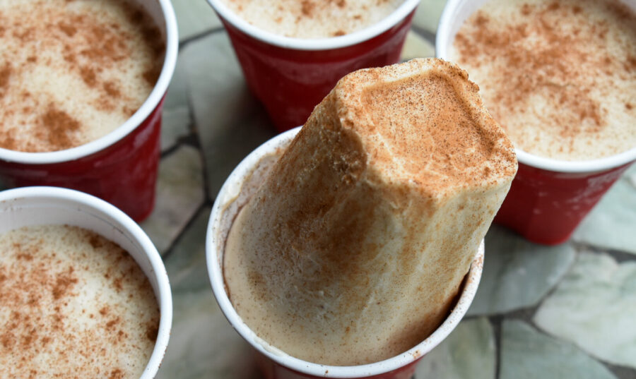 Vasos rojos con Limbers de Coco con canela, un postre congelado tradicional de Puerto Rico, uno de ellos parcialmente desmoldado mostrando su textura cremosa.