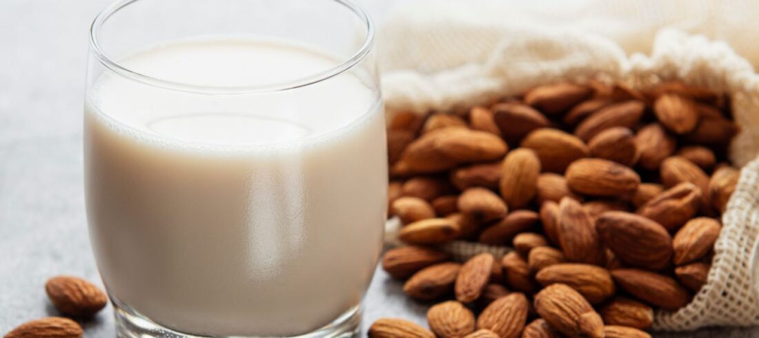 Leche de almendra en vaso junto a almendras enteras, ejemplo de bebida vegetal como alternativa no láctea a la leche.