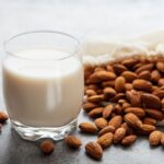 Leche de almendra en vaso junto a almendras enteras, ejemplo de bebida vegetal como alternativa no láctea a la leche.