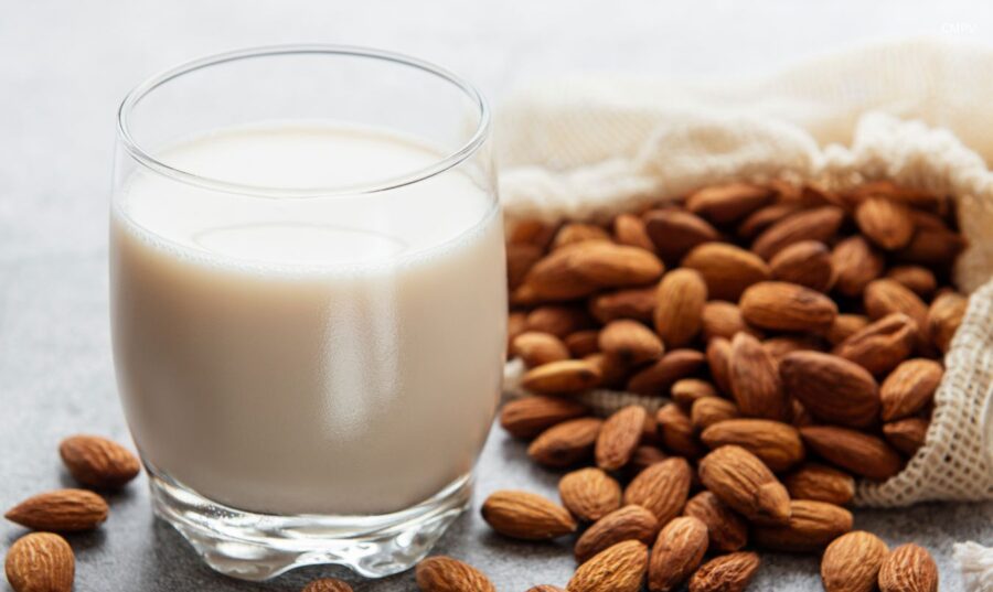 Leche de almendra en vaso junto a almendras enteras, ejemplo de bebida vegetal como alternativa no láctea a la leche.