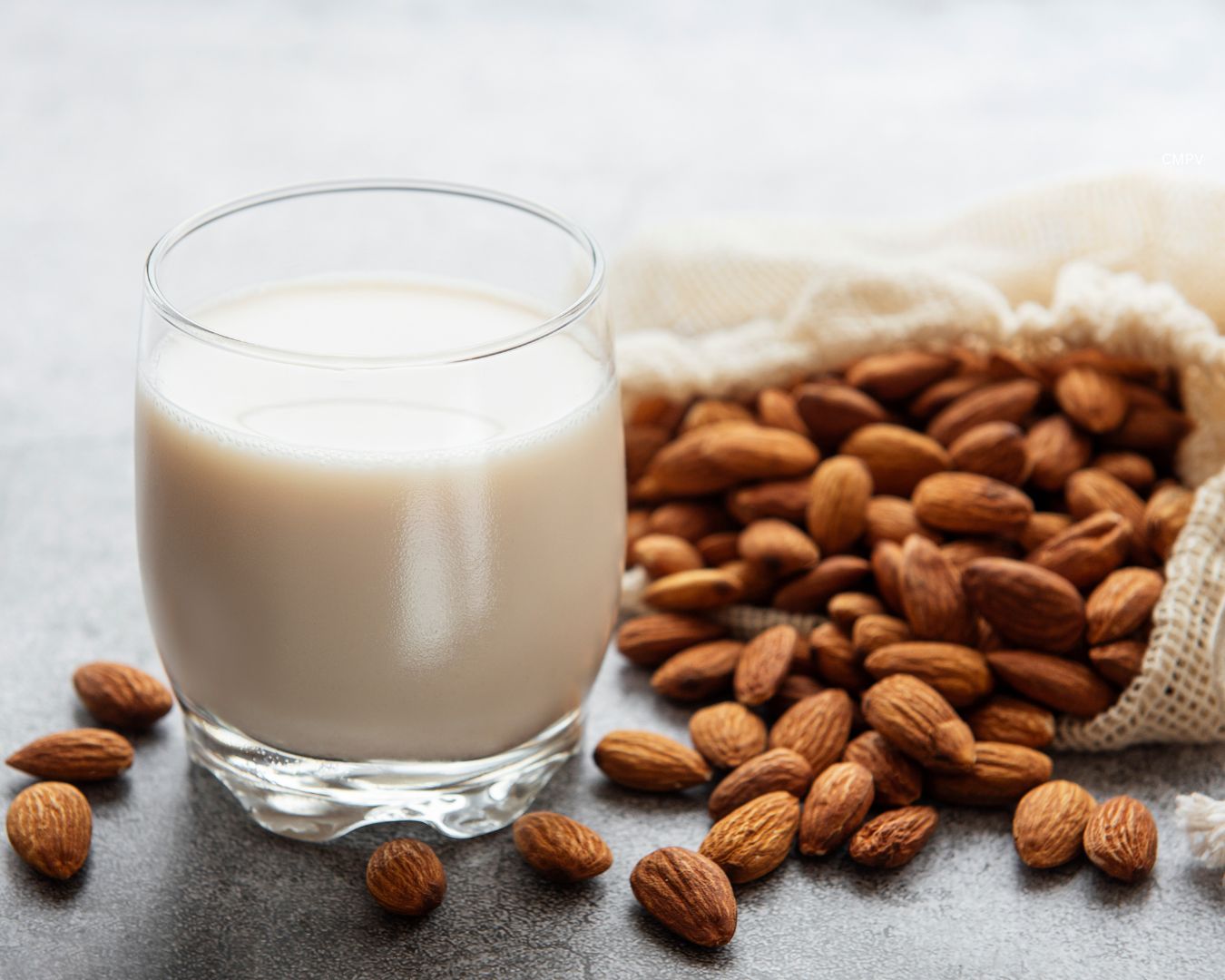 Leche de almendra en vaso junto a almendras enteras, ejemplo de bebida vegetal como alternativa no láctea a la leche.