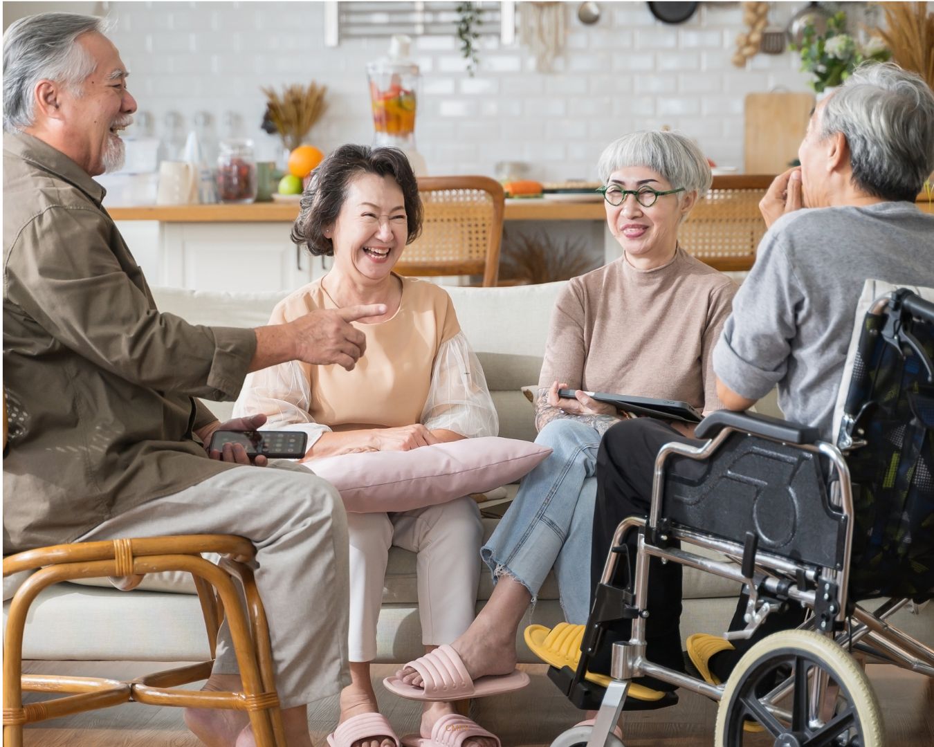 Grupo de adultos mayores conversando y sonriendo en una sala; uno de ellos utiliza una silla de ruedas.