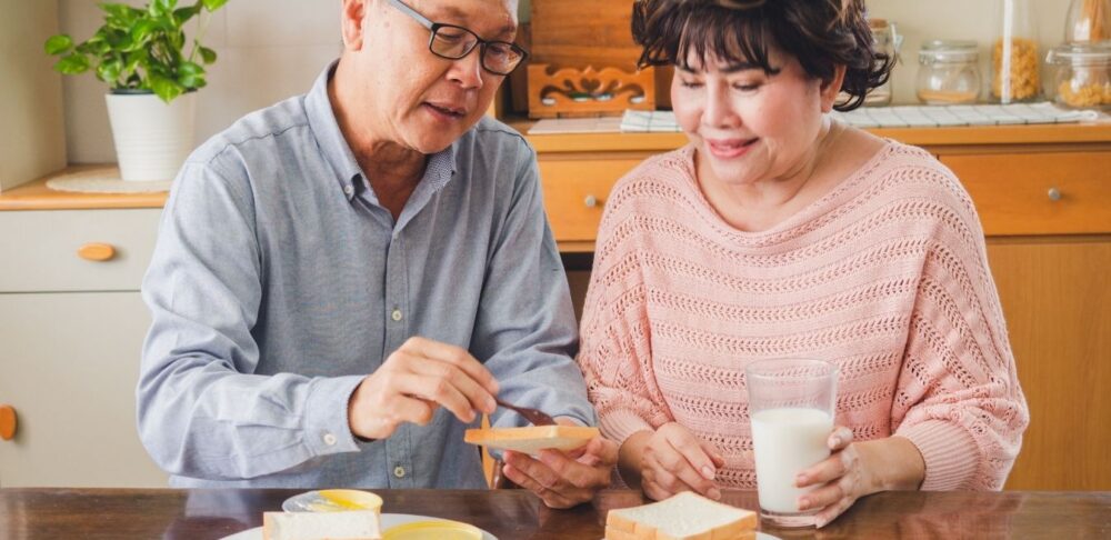 Pareja de adultos mayores comparte un desayuno en casa mientras practica una alimentación consciente basada en las señales de hambre y saciedad.