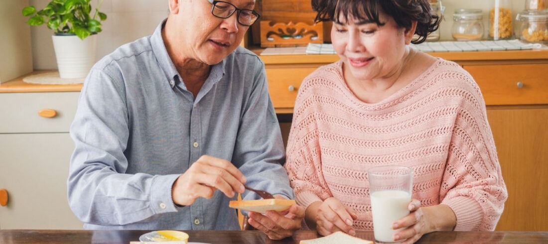 Pareja de adultos mayores comparte un desayuno en casa mientras practica una alimentación consciente basada en las señales de hambre y saciedad.