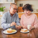 Pareja de adultos mayores comparte un desayuno en casa mientras practica una alimentación consciente basada en las señales de hambre y saciedad.