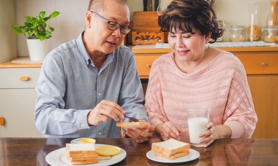Pareja de adultos mayores comparte un desayuno en casa mientras practica una alimentación consciente basada en las señales de hambre y saciedad.